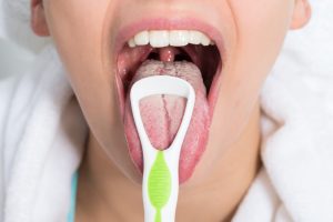 舌クリーナーで舌苔を取り除く女性