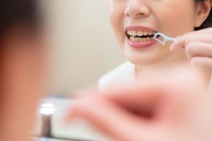 フロスを使い歯間を掃除する女性