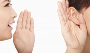 女性が手を口に当ててと何の人に何かを言う