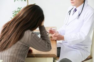 頭痛の症状を医師に相談している女性